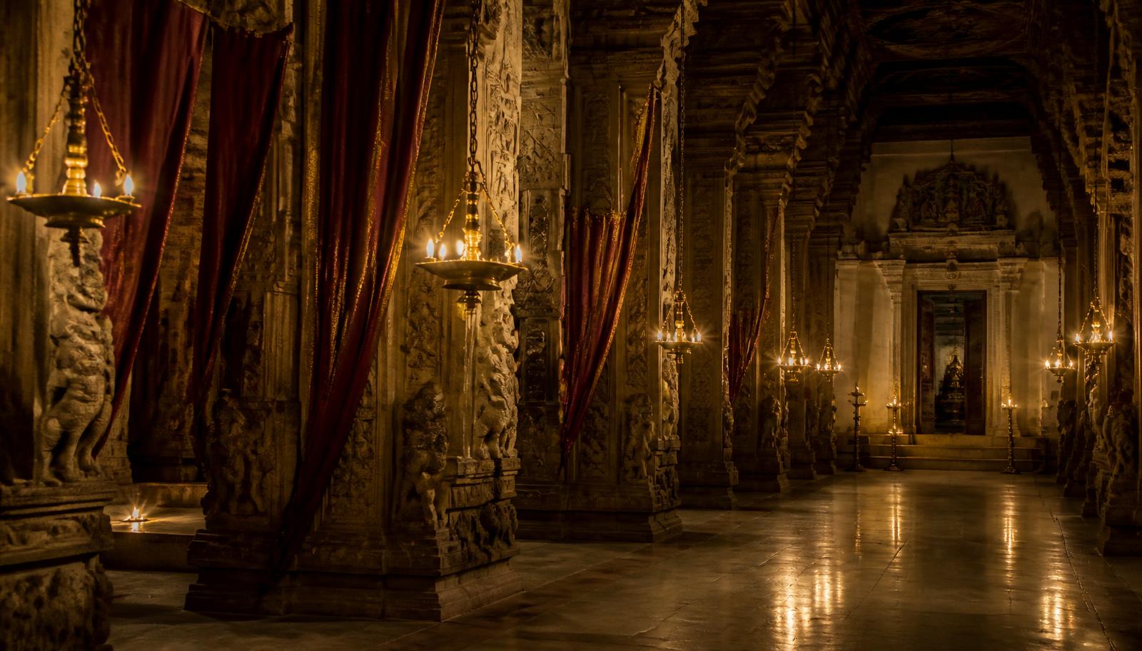 Palace corridor with carved stone pillars and hanging brass lamps